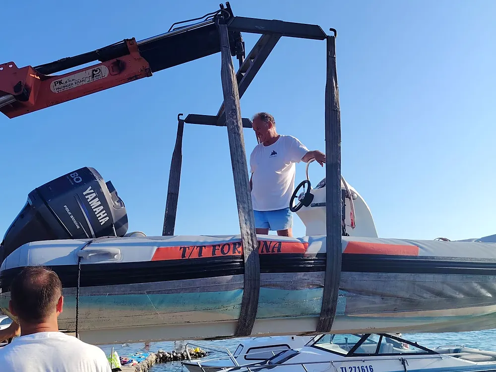 Inflatable boat with a Yamaha 80 engine in the crane slings above the sea