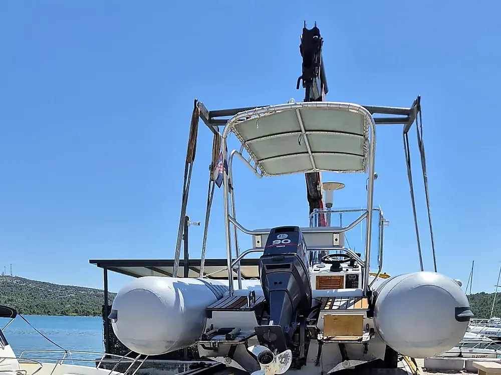 Inflatable boat with a Yamaha 90 engine on the crane truck in the marina